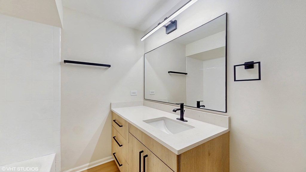 A bathroom with a sink, mirror, and wooden cabinets.
