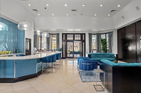 A modern kitchen with blue chairs and a black counter.