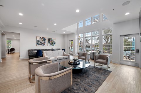 A modern living room with a glass table and grey chairs.