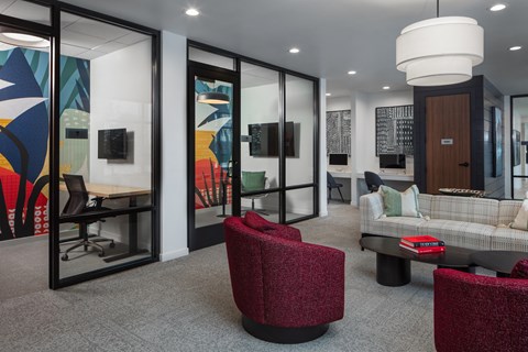 A modern living room with a grey sofa, a red chair and a glass wall.