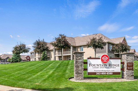 A sign for Fountain Ridge Lounge Apartment Homes is in front of a building.