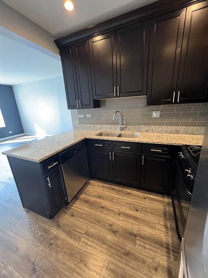 an empty kitchen with wooden floors and black cabinets