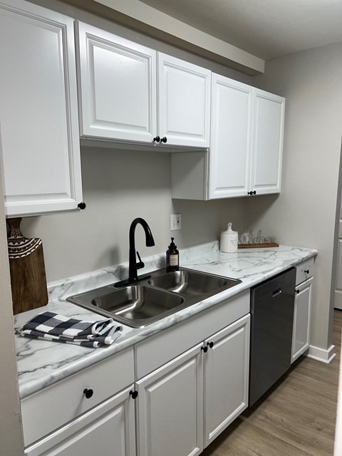 A kitchen with white cabinets and a marble countertop.