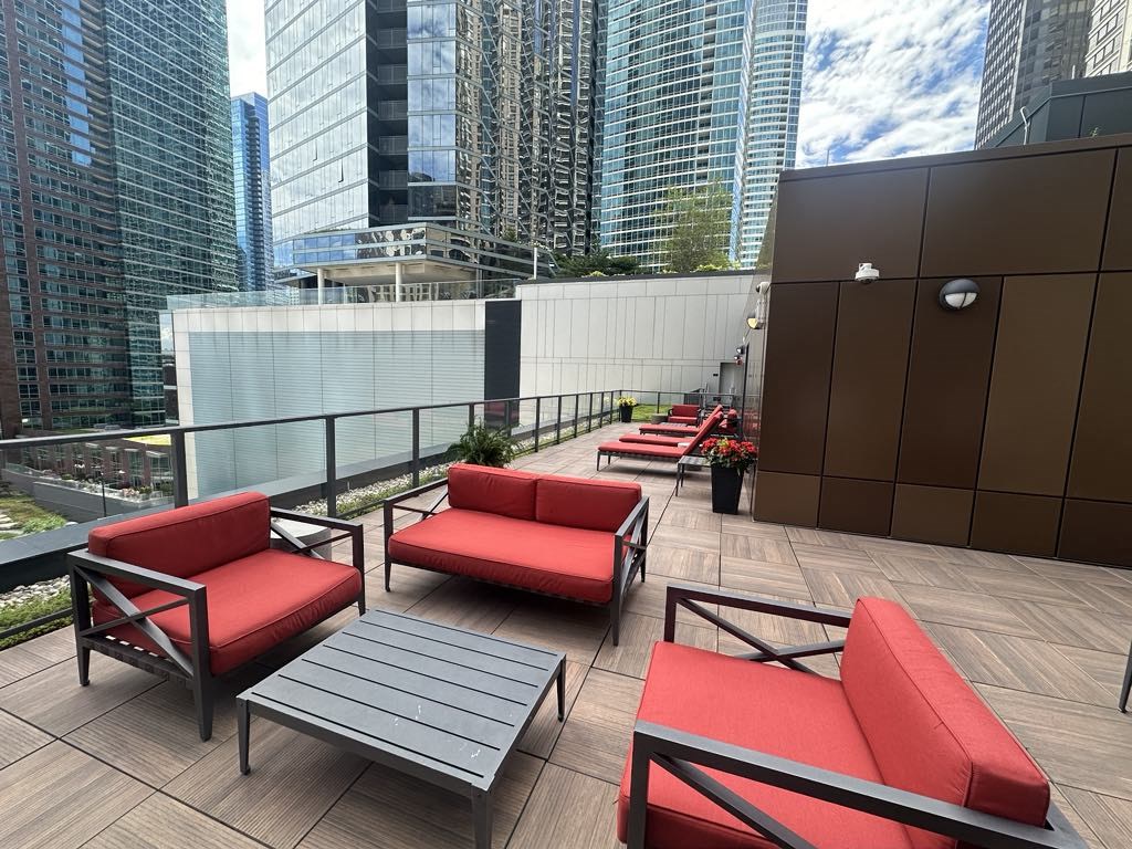 a terrace with red couches and tables on a balcony with skyscrapers