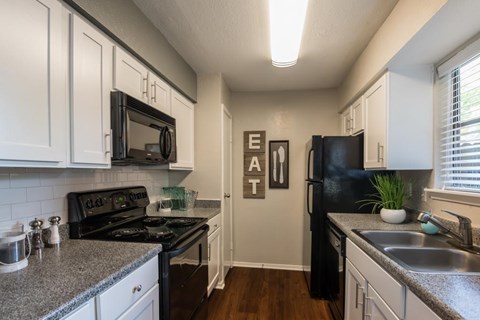 A kitchen with a black refrigerator and a sign that says "EAT".