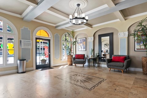 A spacious lobby with a chandelier, sofas, and a large rug at the Brookmore Apartments leasing office.