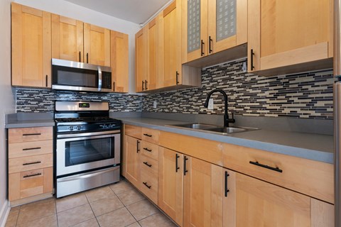 A kitchen with wooden cabinets and a stone backsplash.