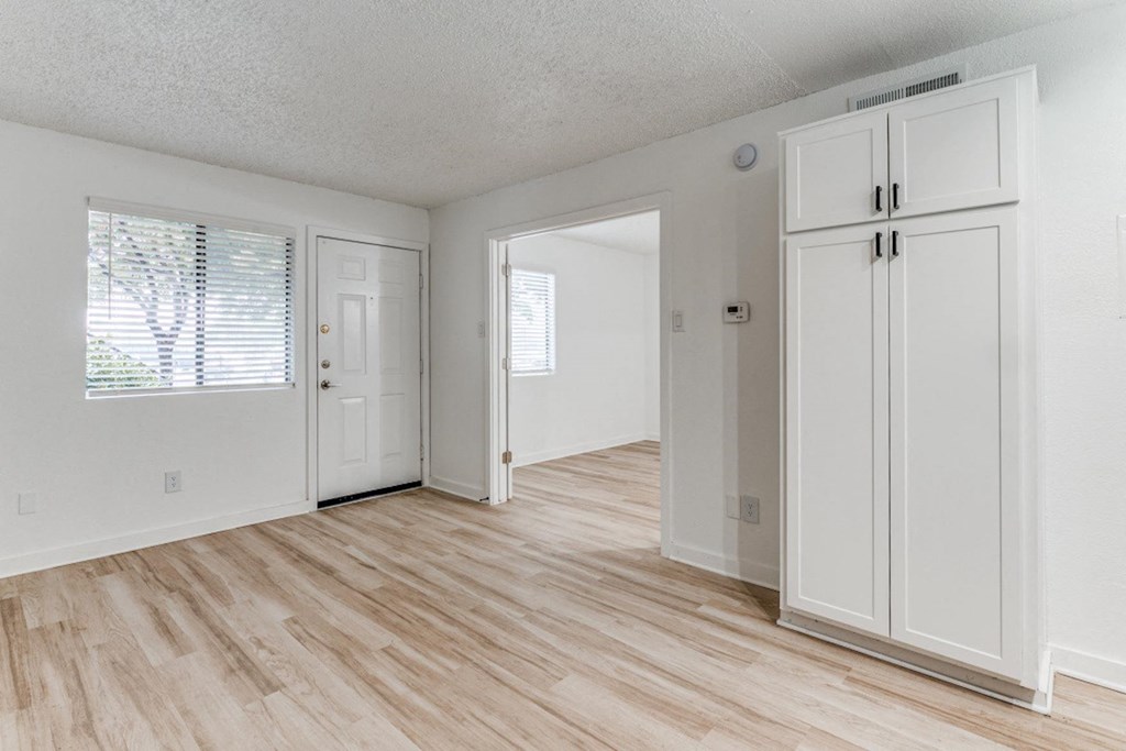 Fusion Fort Worth renovated one bedroom apartment in Haltom City, TX with light wood plank flooring, large white cabinets and double bedroom door.