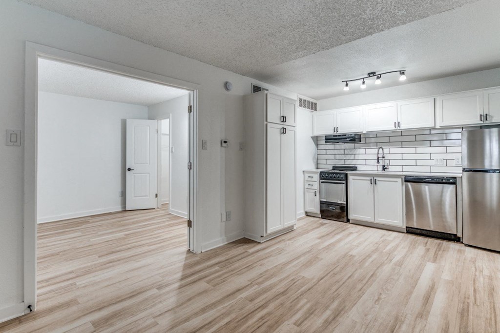 Fusion Fort Worth renovated apartment in Haltom City, TX with light wood plank flooring, stainless steel appliances, and subway tile backsplash.