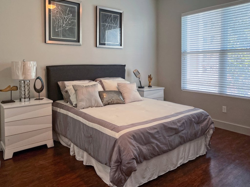 Bedroom in State Street Flats one bedroom apartment in Nashville with queen bed, two modern nightstands, and large window with blinds.