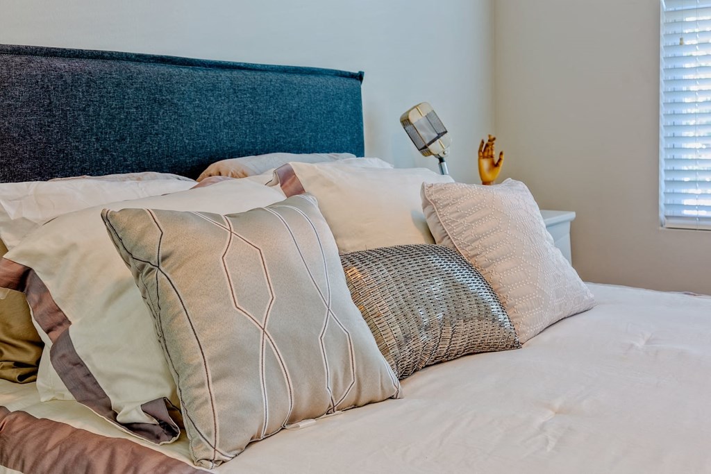 Bed in State Street Flats one bedroom apartment in Nashville with plush fabric headboard, white luxury duvet, and 7 modern pillows.