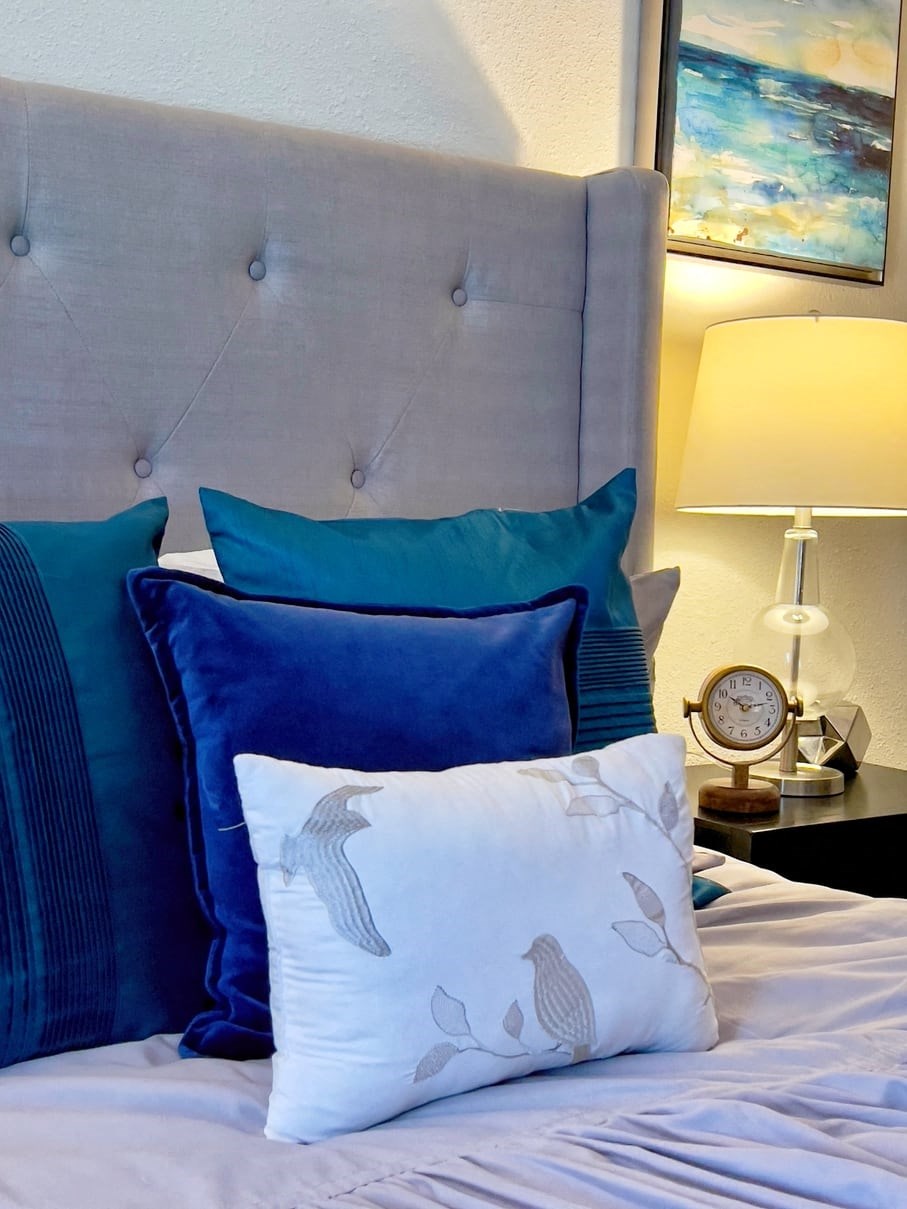 Bed in the Retreat at Indian Lake one bedroom apartment in Hendersonville with luxury velvet pillows and vintage clock on bedside table.