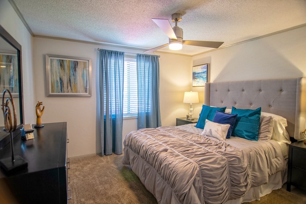 Bedroom in the Retreat at Indian Lake in Hendersonville with modern ceiling fan, queen bed, and large window with blinds and curtains.