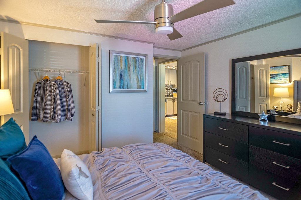 Bedroom in the Retreat at Indian Lake in Hendersonville with modern ceiling fan, closet, and six-drawer dresser with vanity mirror.