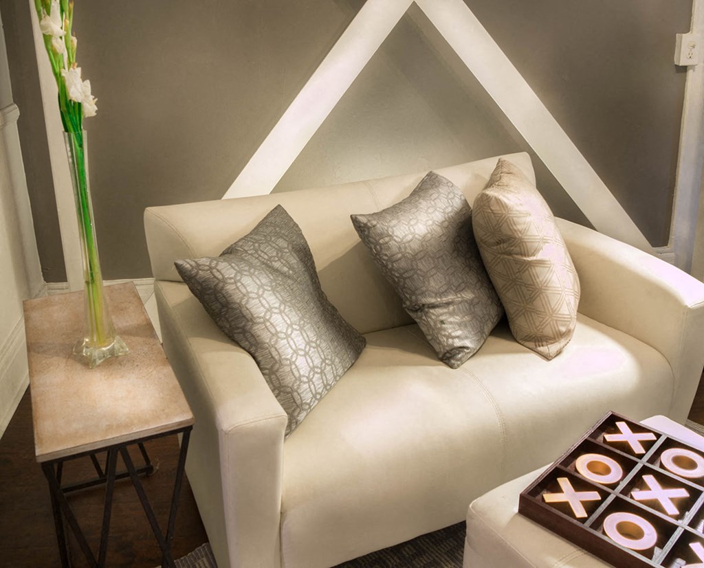 Brookmore apartments Pasadena - Modern Cream Sofa with grey and cream throw pillows, End Table with tall flower vase, and Hardwood-Inspired Flooring in living room sofa area