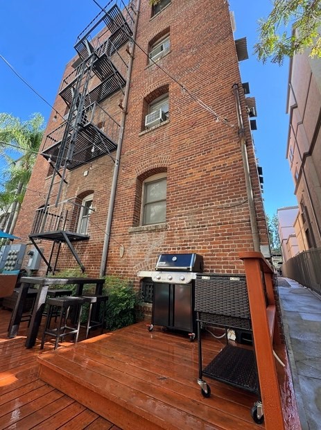 Brookmore Apartments wooden deck with a barbecue grill and a chair.