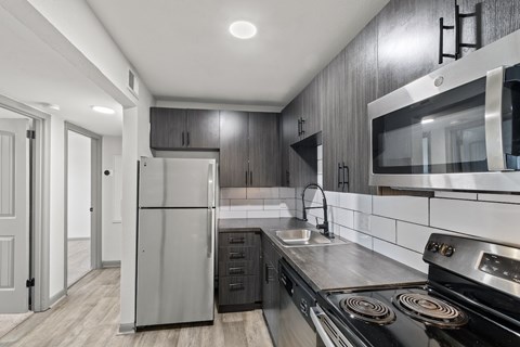 The Canvas Apartments modern kitchen with a stainless steel refrigerator and oven.