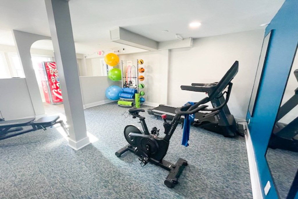 Gym in The Canvas apartments in Nashville, Tennessee with cardio machines, exercise balls, yoga mats, and Coca Cola vending machine.