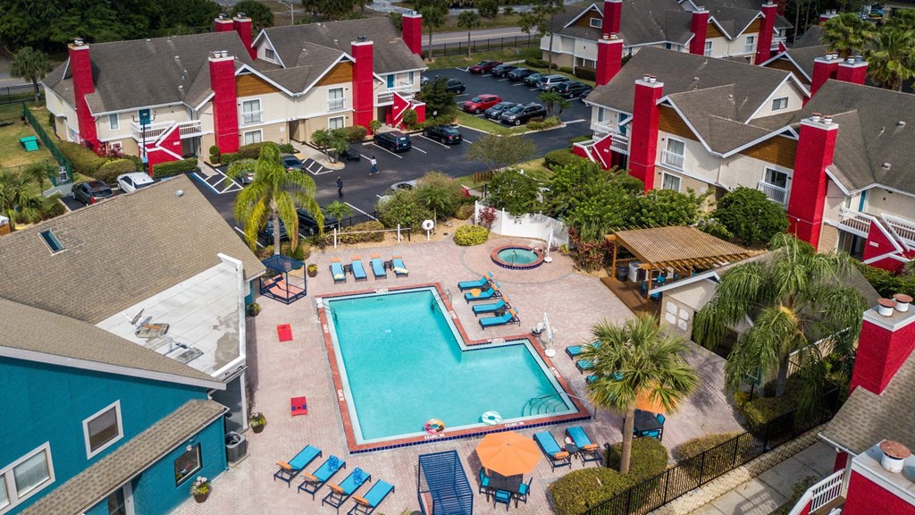 Aerial shot of community pool surrounded by Fusion Orlando apartment buildings. Buildings are two stories and have red chimneys and stairwells.