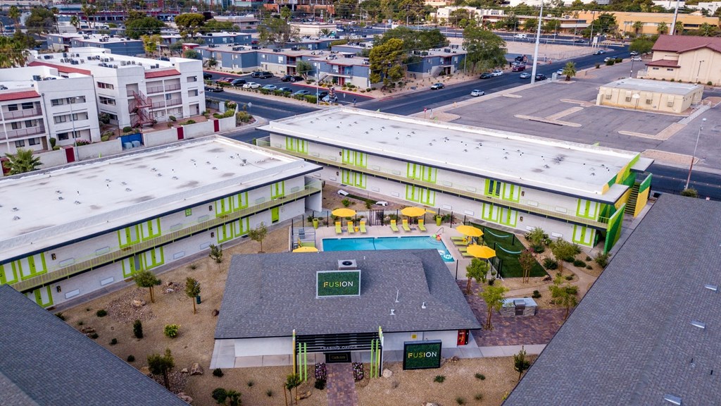 Aerial view of Las Vegas fusion apartments with bright green doors around clubhouse and community pool in desert landscape