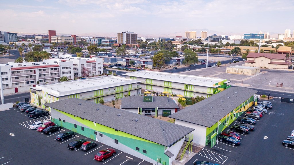 Aerial view of four Las Vegas Fusion apartment buildings in a square around amenities house with Las Vegas skyline in background