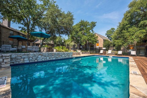 Fusion 35 swimming pool surrounded by a stone wall and trees.