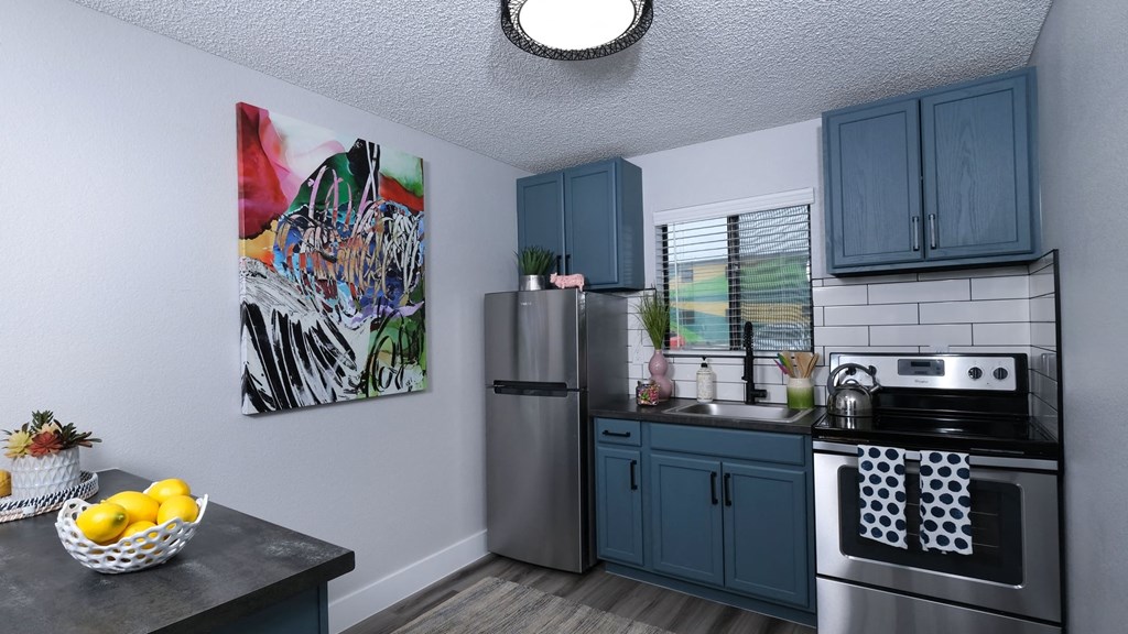 Fusion Las Vegas apartment kitchen with colorful modern painting, large window above the sink, and island with bowl of lemons.