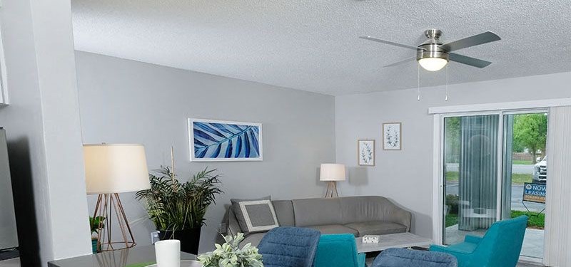 Living Room View from kitchen to living room in Mandarin Bay apartments in Jacksonville, FL. Living room is large with blue and grey midcentury seating.