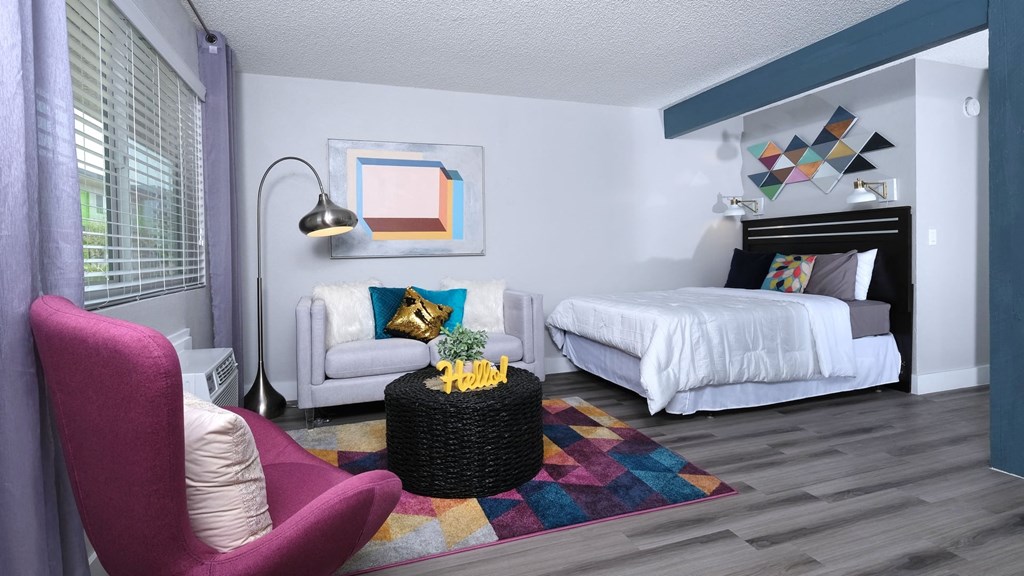 Fusion Las Vegas studio apartment sleeping and living area with large bed, geometric rug and decor, and black wicker coffee table.