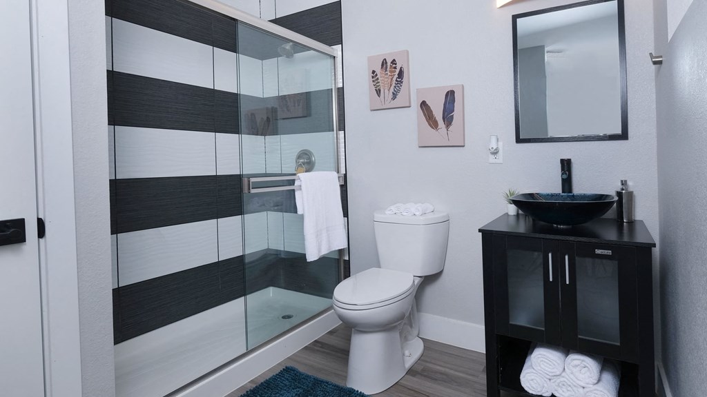 Fusion Las Vegas apartment bathroom with basin sink and black and modern black and white tiled shower with sliding glass door.