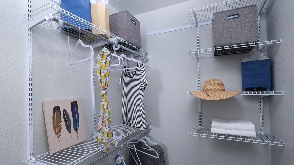 Fusion Las Vegas apartment closet with grey and blue cloth storage boxes, towels, and hangers on built in wire shelving.