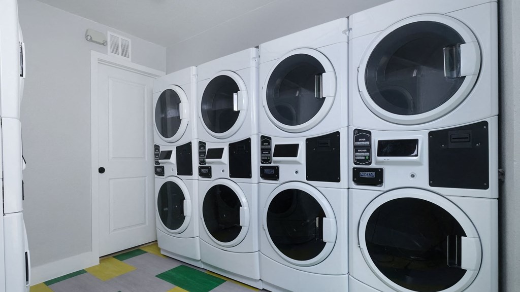 Fusion Las Vegas apartments on site laundry room with four washer dryer units and yellow, green, and grey tile floor.