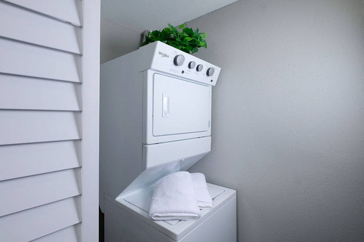 Mandarin Bay apartments in Jacksonville, FL in-unit laundry. Machine is a stacked whirlpool washer and dryer in a closet with shuttered door