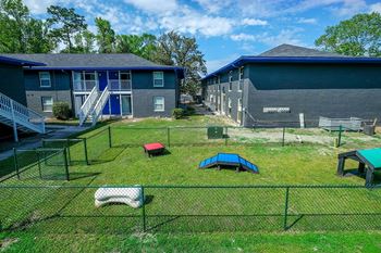 Dog park at Mandarin Bay Apartments in Jacksonville with lush grass, green fence, and exercise equipment.
