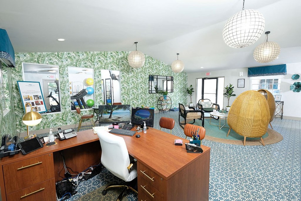 Watermarq Apartments Clubhouse in Lakeland, Fl with large leasing desk, modern lighting, and tropical palm wallpaper accent wall.