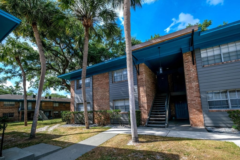 Outdoor shot of Watermarc Apartment complexes in Lakeland, Fl with two story brick buildings surrounded by palm trees and grass.