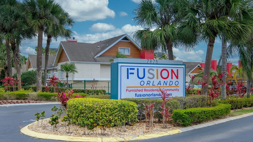Fusion Orlando apartments street sign that reads "Furnished Residential Community" surrounded by tropical landscaping and palm trees.
