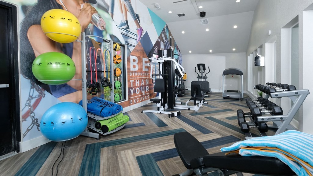 Fusion Orlando apartment fitness center with exercise balls, yoga mats, dumbbells, and cardio machines on modern herringbone floor.