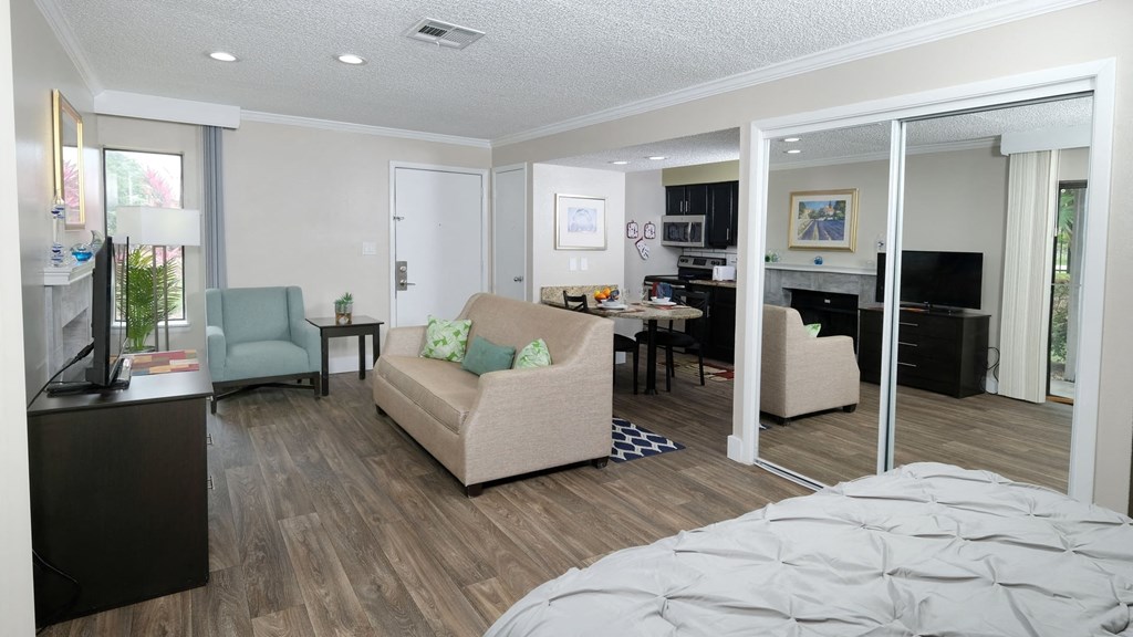 Fusion Orlando efficiency studio apartments Orlando, FL kitchen and spacious living room area with wood inspired plank flooring and large mirrored closet doors.