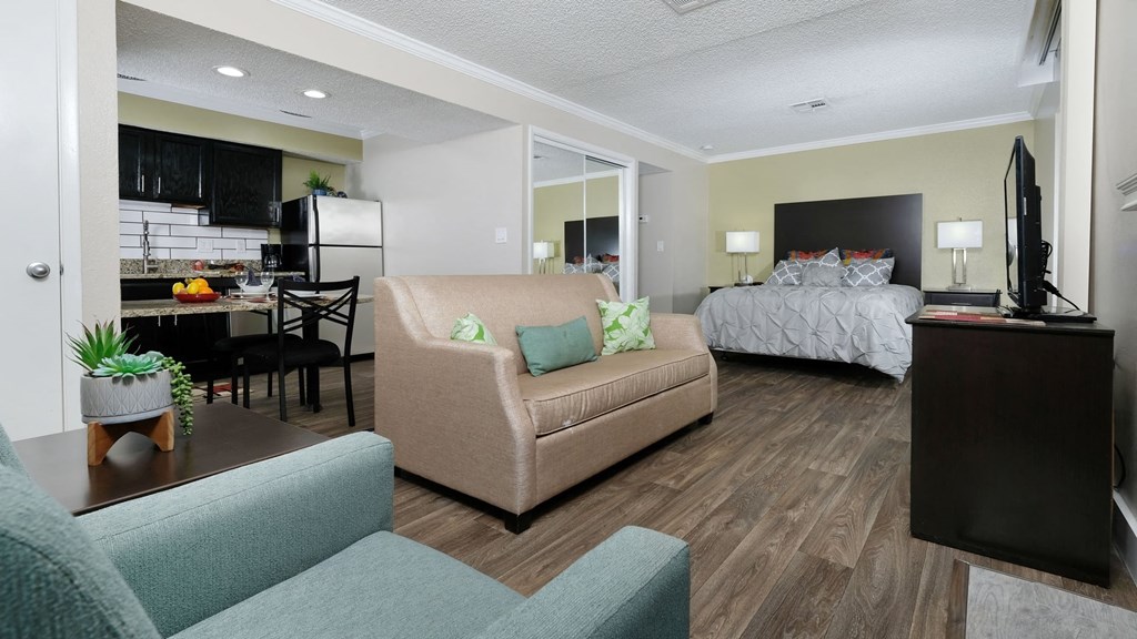Fusion Orlando furnished studio apartment with large bed with night stands, spacious living room area, and kitchen with breakfast nook.