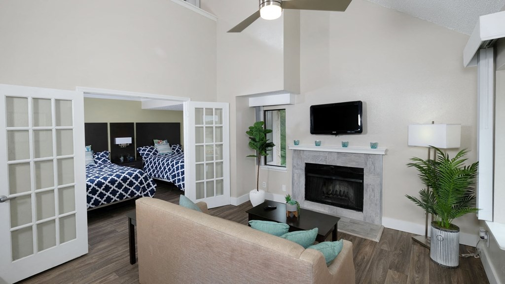 Fusion Orlando furnished apartment living room with built in fireplace, vaulted ceiling with modern fan, and tan couch with teal pillows.