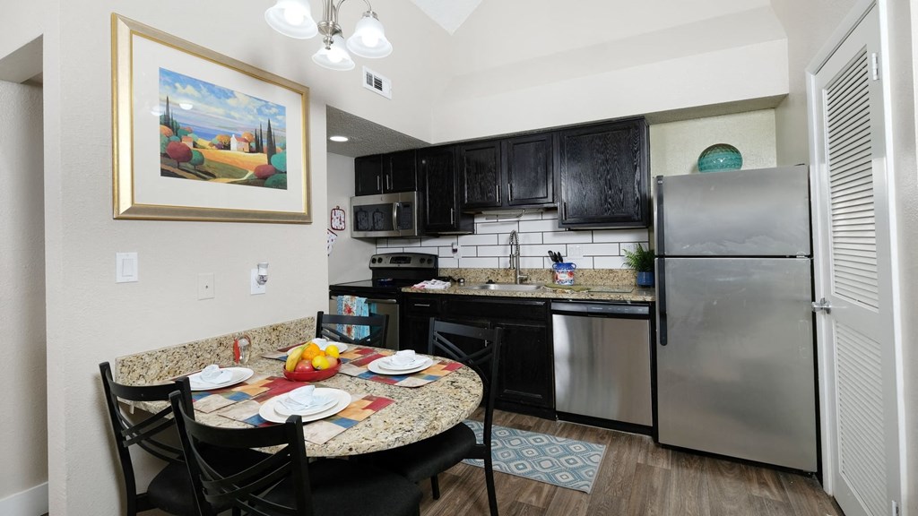 Fusion Orlando apartment in Orlando kitchen with dinette and stainless steel microwave, dishwasher, refrigerator, and electric stove.