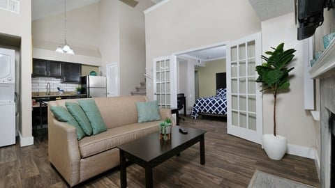 Apartments Orlando FL - Fusion Orlando - Open Living Room With High Ceilings, Wood-Style Flooring, Stylish Couch, Coffee Table, and Access to the Kitchen and Bedroom