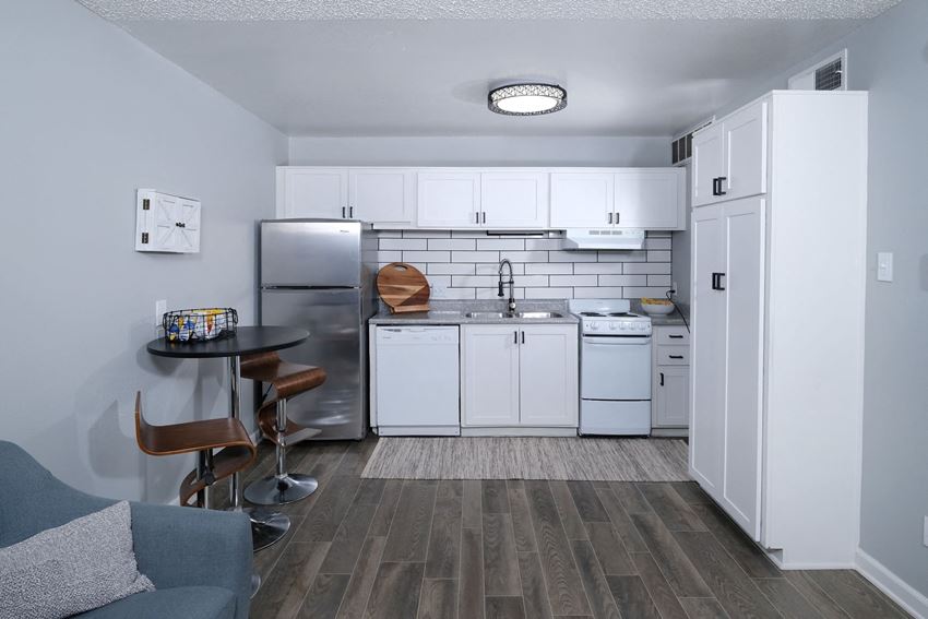 Fusion Fort Worth - Classic Kitchen Apartments for Rent Haltom City TX - Fusion Fort Worth - Kitchen with Hardwood-Inspired Flooring, Tiled Backsplash, White Cabinets, and Dining Area - Photo Gallery
