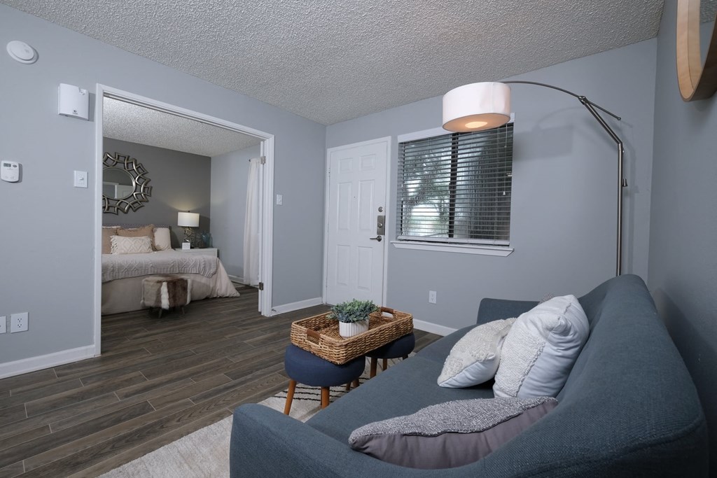 Fusion Fort Worth one bedroom apartment in Haltom City living area with wide door to bedroom furnished with large bed and modern blue couch.