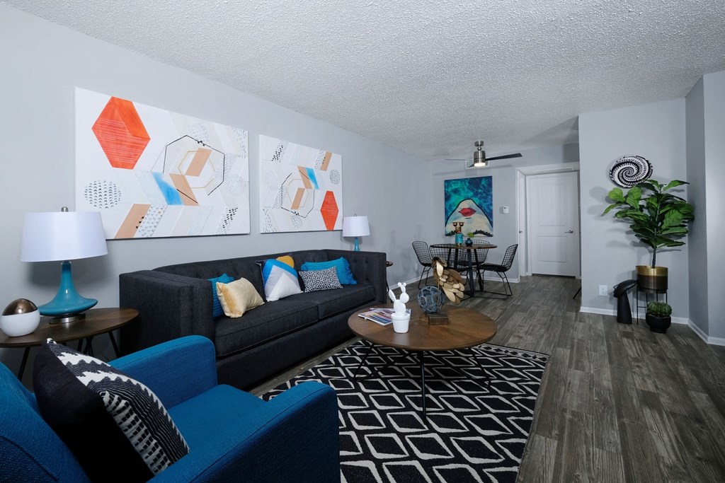 Open concept Living room and dining room in Studio 700 apartment in Arlington, TX with modern ceiling fan and luxury plank flooring throughout.