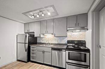 A modern kitchen with stainless steel appliances and wooden flooring at The Retreat at Indian Lake studio and 1 bedroom apartments in Hendersonville TN.
