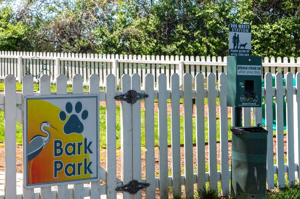 Pet park at the Retreat at Indian Lake apartments in hendersonville with dog waste station and white picket fence with "Bark Park" sign.