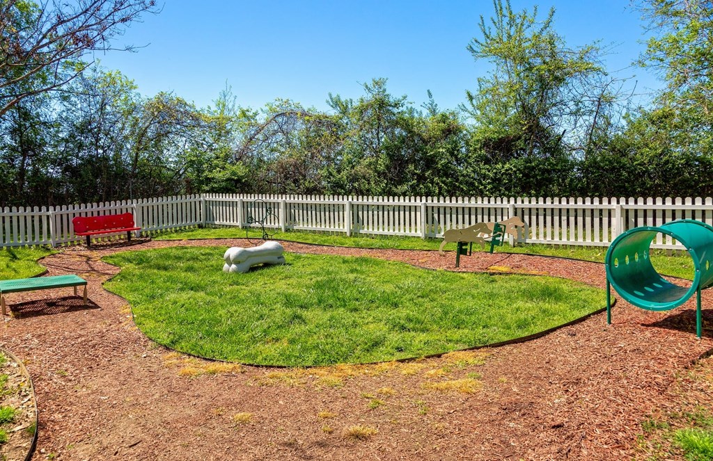 Pet park at the Retreat at Indian Lake apartments in hendersonville with dog agility course, red park bench, and white picket fence.