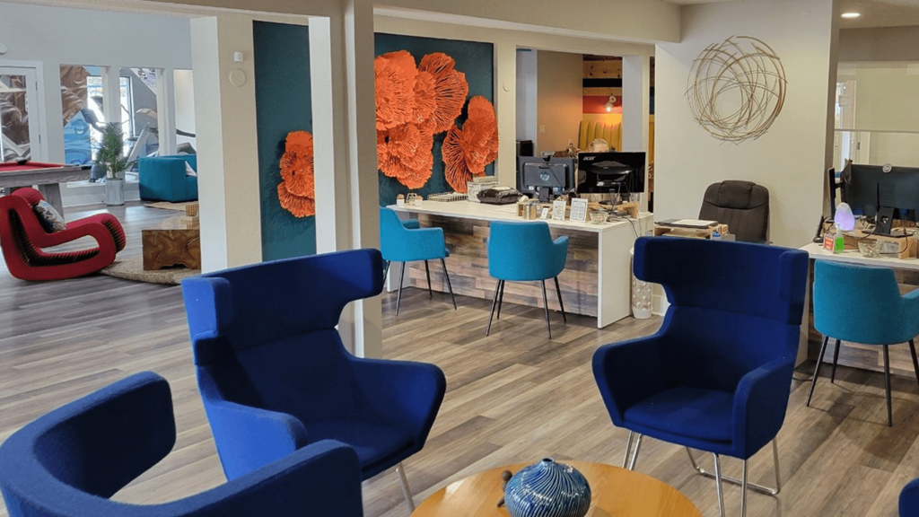 Fusion Orlando apartments entryway with desks with computers and waiting area with modern navy blue chairs around a wood coffee table.